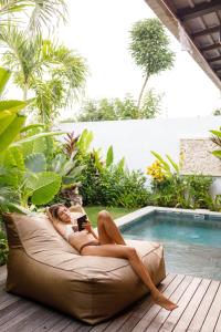 a woman laying on a couch next to a swimming pool at Di Cappio Studio Uluwatu in Uluwatu