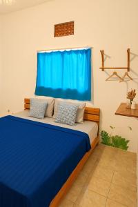 a bedroom with a blue bed with a blue curtain at Casa De' Summer Banyuwangi in Banyuwangi