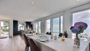 een eetkamer met een tafel met paarse bloemen in een vaas bij Au point de vue in Perros-Guirec