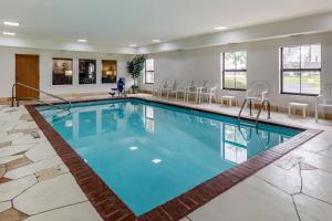 a swimming pool in a hotel with chairs around it at Comfort Inn Walcott near Davenport in Walcott