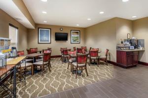 a restaurant with tables and chairs and a tv at Comfort Inn Walcott near Davenport in Walcott