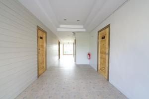 an empty hallway with wooden doors and a tile floor at Little Rooms in Chanthaburi