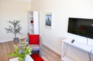 a living room with a flat screen tv and a chair at Am Rundsteg 9 in Burgtiefe auf Fehmarn  +11 photos