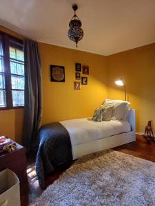 a bedroom with a bed with yellow walls and a rug at Fecskefészek vendégház in Nagymaros