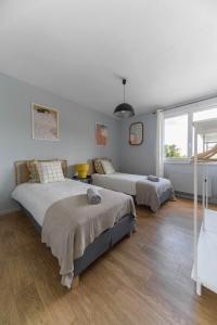two beds in a bedroom with white walls and wood floors at Le Raymond - Appartement proche du centre sportif, des rives de l'Allier et du centre-ville - parking in Vichy +31 photos