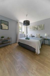 a bedroom with a large bed and wooden floors at Le Raymond - Appartement proche du centre sportif, des rives de l'Allier et du centre-ville - parking in Vichy