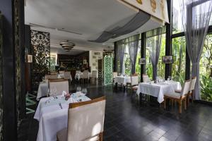 ein Restaurant mit weißen Tischen und Stühlen und Fenstern in der Unterkunft Lynnaya Urban River Resort in Siem Reap