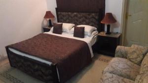 a bedroom with a bed with two lamps and a couch at Bentley Boutique Hotel in Islamabad