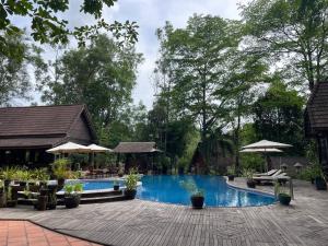 a pool at a resort with chairs and umbrellas at Kirirom Hillside Resort in Kampong Speu