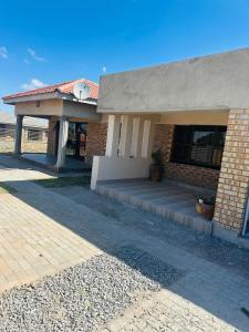 a brick building with a porch with a clock on it at Knovi Guesthouse in Bulawayo