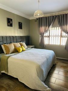 a bedroom with a large bed with yellow pillows at Knovi Guesthouse in Bulawayo +14 photos
