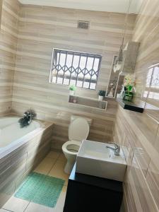 a bathroom with a tub and a toilet and a sink at Knovi Guesthouse in Bulawayo