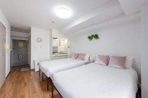 two beds in a room with white walls and wooden floors at アスピア305 Easy access to Shinjuku 1-minute walk from Koshinzuka Station in Tokyo