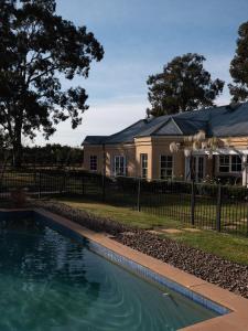 a house with a swimming pool in front of a fence at Vinden Estate Homestead, Pokolbin in Pokolbin
