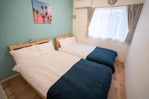 zwei Betten in einem kleinen Schlafzimmer mit Fenster in der Unterkunft 家族の笑顔 希望ヶ丘ビーチまで徒歩5分でのんびり家族ステイ Coral Onnason in Onna