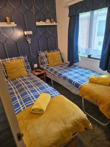 two beds in a room with blue and yellow sheets at Unique Caravan with Outdoor Space in Ballantrae