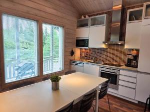 a kitchen with white cabinets and a table with chairs at Villa Chalet - 10 hlö, Himos Länsihuippu in Jämsä