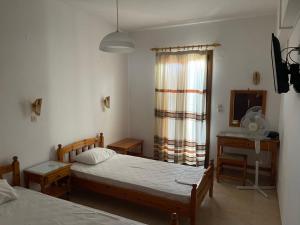 a bedroom with two beds and a desk and a window at Matina's house in Samos