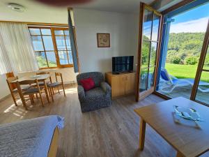 ein Wohnzimmer mit Fernseher und Tisch und Stühlen in der Unterkunft Ferienland Sonnenwald Ferienwohnung im Sonnenwald Apartment 5 in Langfurth 