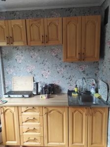 a kitchen with wooden cabinets and a sink at Flowery apartment in Jūrmala