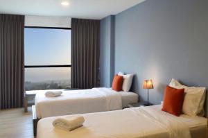 a hotel room with two beds and a window at Suntria Hotel Pattaya in Na Jomtien