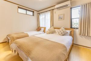 two beds in a room with two windows at TokyoTokyo in Wada