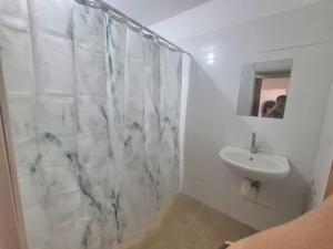 een witte badkamer met een wastafel en een douche bij Family vacation in Tiberias
