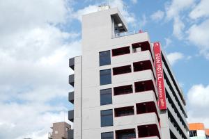 Un edificio alto y blanco con un cartel rojo. en Sun Hotel Funabashi, en Funabashi
