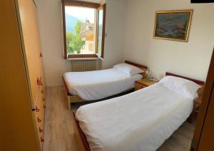 two beds in a small room with a window at Appartamento Bosco al Sole in San Lorenzo in Banale