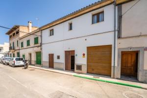 a white building with wooden garage doors on a street at Ideal Property Mallorca - Villa Placeta in Sa Pobla