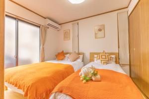 two beds in a room with orange sheets at tokyo in Wada
