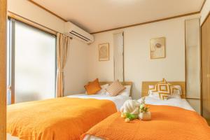 two beds in a room with orange sheets at tokyo in Wada