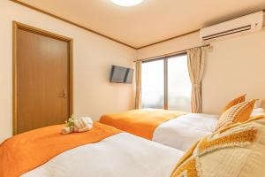two beds in a room with a window at tokyo in Wada