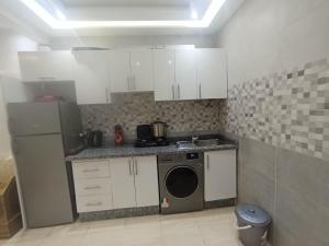 a kitchen with white cabinets and a washer and dryer at Appartement a Oued laou complexe cité cinter in Oued Laou