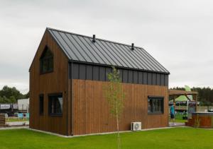 a small house with a black roof at Stodoła HowSmart in Grady Szlacheckie