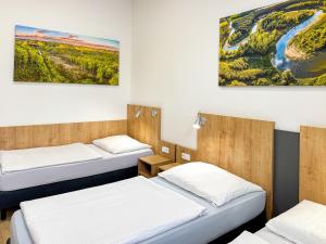 a room with three beds and a painting on the wall at Ubytovna U Kašny in Uherské Hradiště