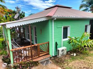 a green tiny house with a porch at Gîte le Colibri, Bouillante - Plage de petite Anse in Bouillante