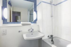a white bathroom with a sink and a bath tub at The Beacon Hotel, Cardiff, Part of the AG Collection in Cardiff +5 photos