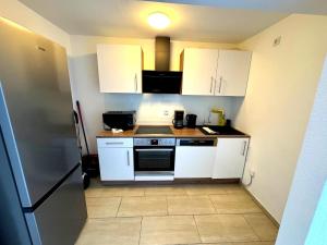 ハムにあるPremium 2 Zimmer 4 Bett Apartment, SmartTV , Terrasseの小さなキッチン(白いキャビネット、冷蔵庫付) +2枚の写真