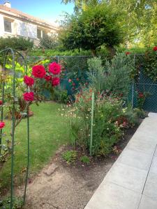 a garden with red roses and a fence at Belle chambre chez Zoa in Noisiel