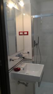 a white bathroom with a sink and a mirror at Casa Origano in Ispica