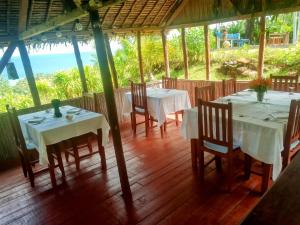 a dining room with white tables and chairs and the ocean at Lambawany in Sainte Marie +64 photos