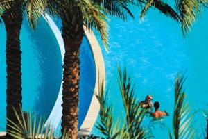 a man and woman in the water at a resort with palm trees at Baron Palms Adults Friendly Only 16 years plus Boutique Hotel Style in Sharm El Sheikh