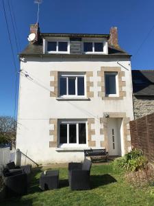 a white house with chairs in front of it at Charmante maison au calme in Saint-Quay-Portrieux