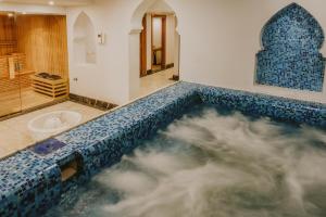 a bathroom with a bath tub with a blue and white tiles at Baron Palms Adults Friendly Only 16 years plus Boutique Hotel Style in Sharm El Sheikh +39 photos