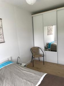 a bedroom with a mirror and a chair and a bed at Charmante maison au calme in Saint-Quay-Portrieux
