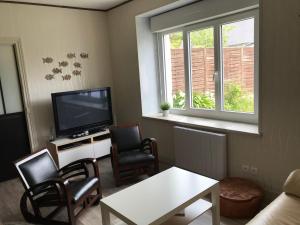 a living room with a tv and a table and chairs at Charmante maison au calme in Saint-Quay-Portrieux
