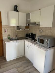 a kitchen with white cabinets and a sink and a microwave at Ferienwohnung -Bernie EG Sandhorst in Aurich