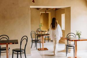 a woman walking through a restaurant with tables and chairs at La Ghiandaia Farmhouse in Conegliano +34 photos