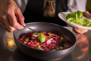 een persoon die een kom voedsel met een lepel vasthoudt bij Boutique Hotel e Chalets Salvadori in Mezzana +110 foto's